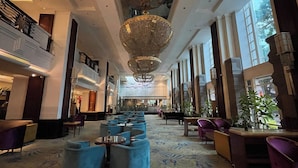 A spacious lobby with a grand chandelier, seating areas, and large windows.