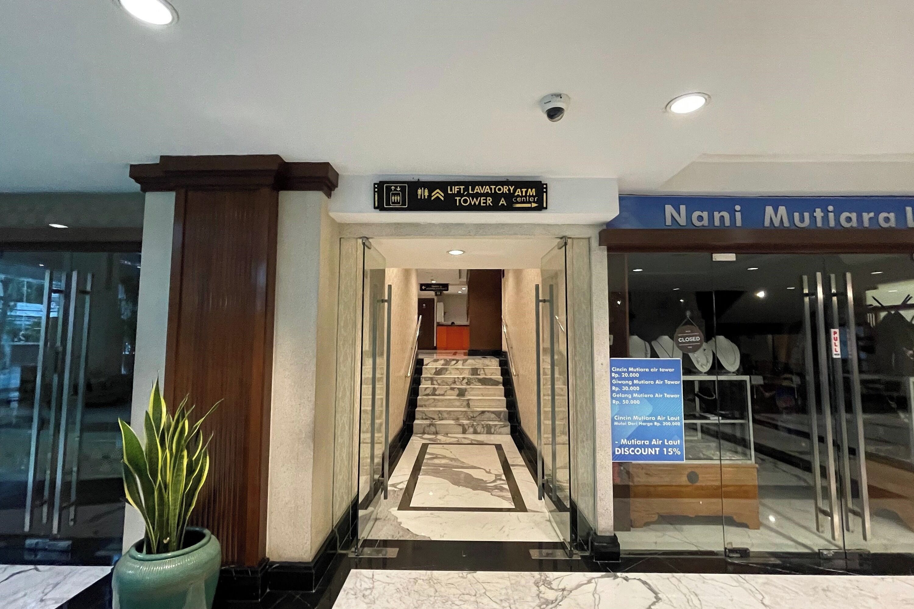 Entrada de un hotel con un cartel que indica el ascensor, los sanitarios y el cajero automático en la Torre A.