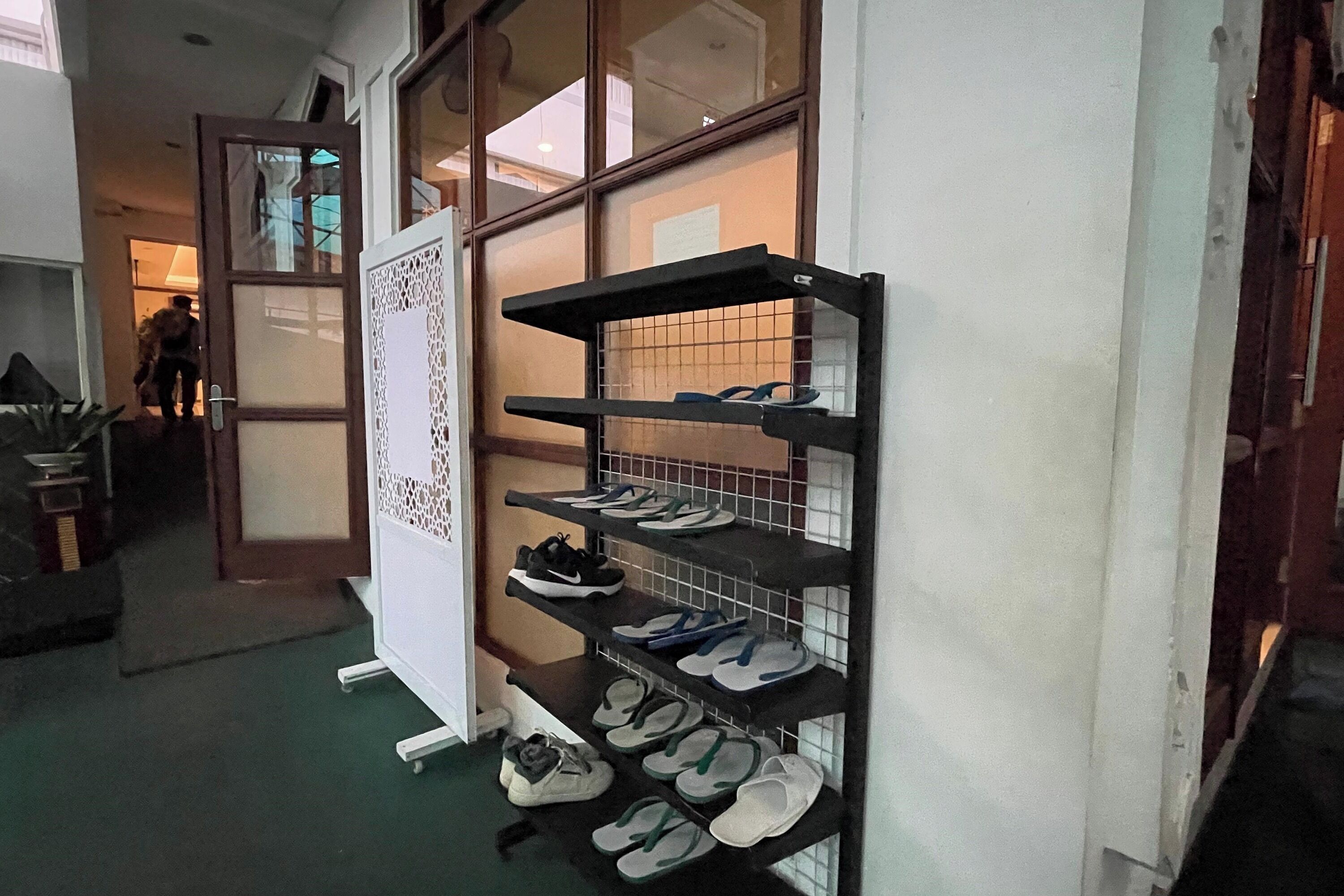 A shoe rack with multiple shelves holding various pairs of shoes.
