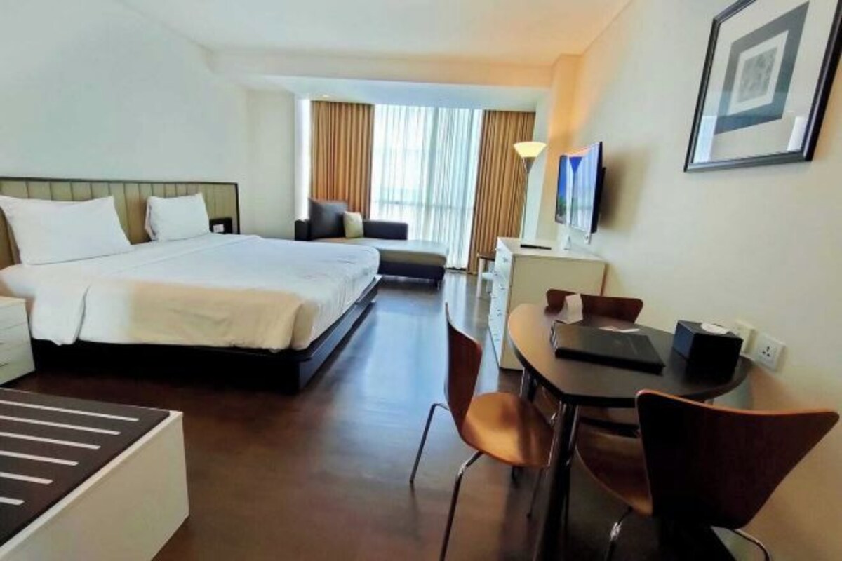 Een hotelkamer met een bed, een bureau, een stoel, een bank en een televisie.