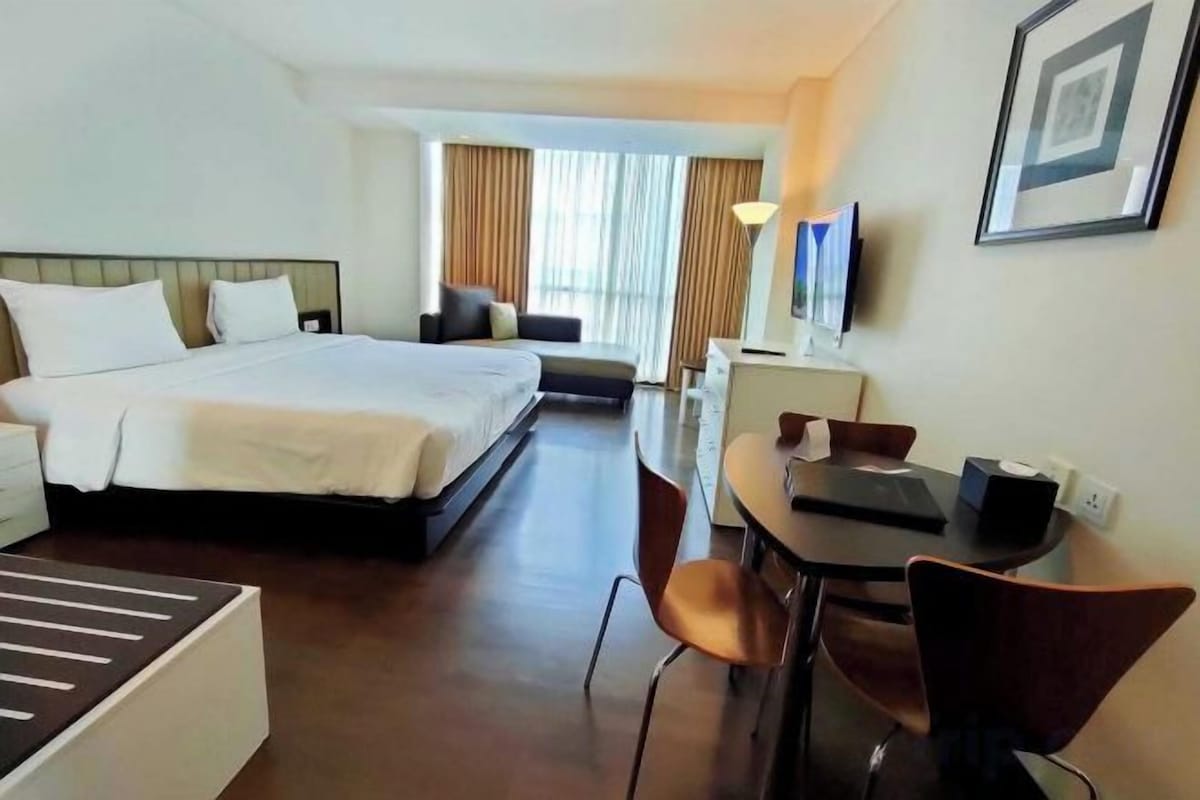 Una habitación de hotel con una cama grande, un escritorio, una silla y un televisor.