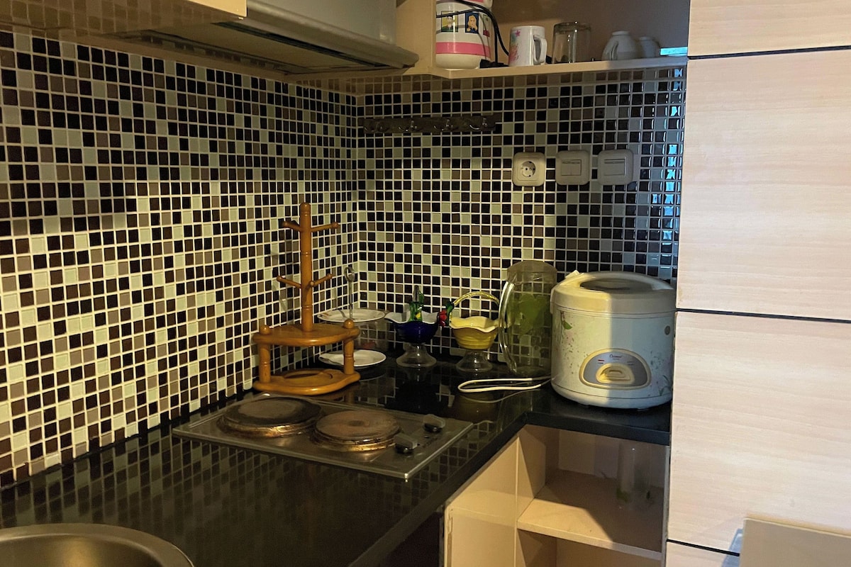 Une cuisine avec un plan de travail recouvert d’un carrelage noir et blanc, une cuisinière, une bouilloire et un four à micro-ondes.