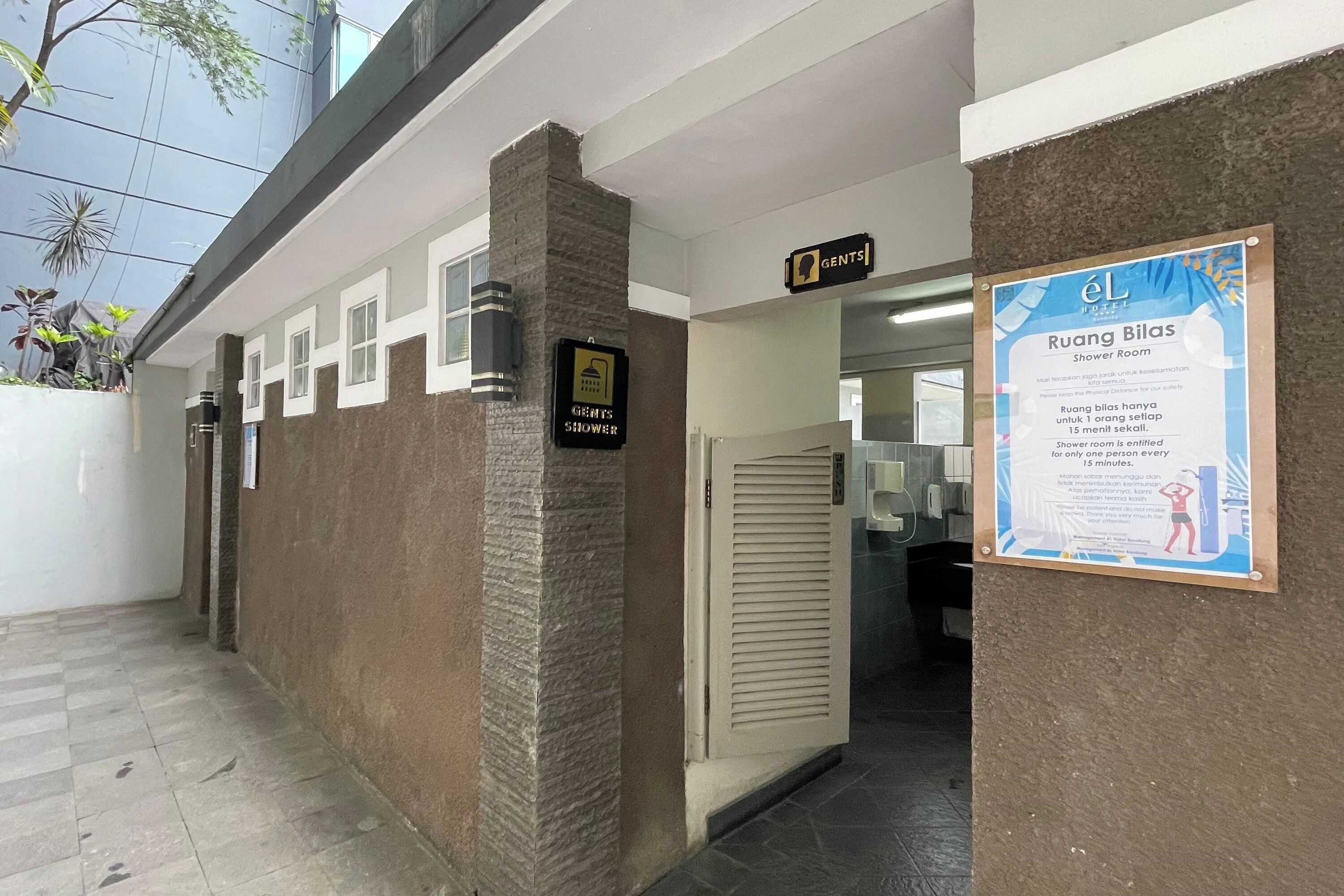 Baño de hombres con señalización indicando que es para hombres, letrero de duchas y un cartel que anuncia un límite de tiempo de 15 minutos para las duchas.