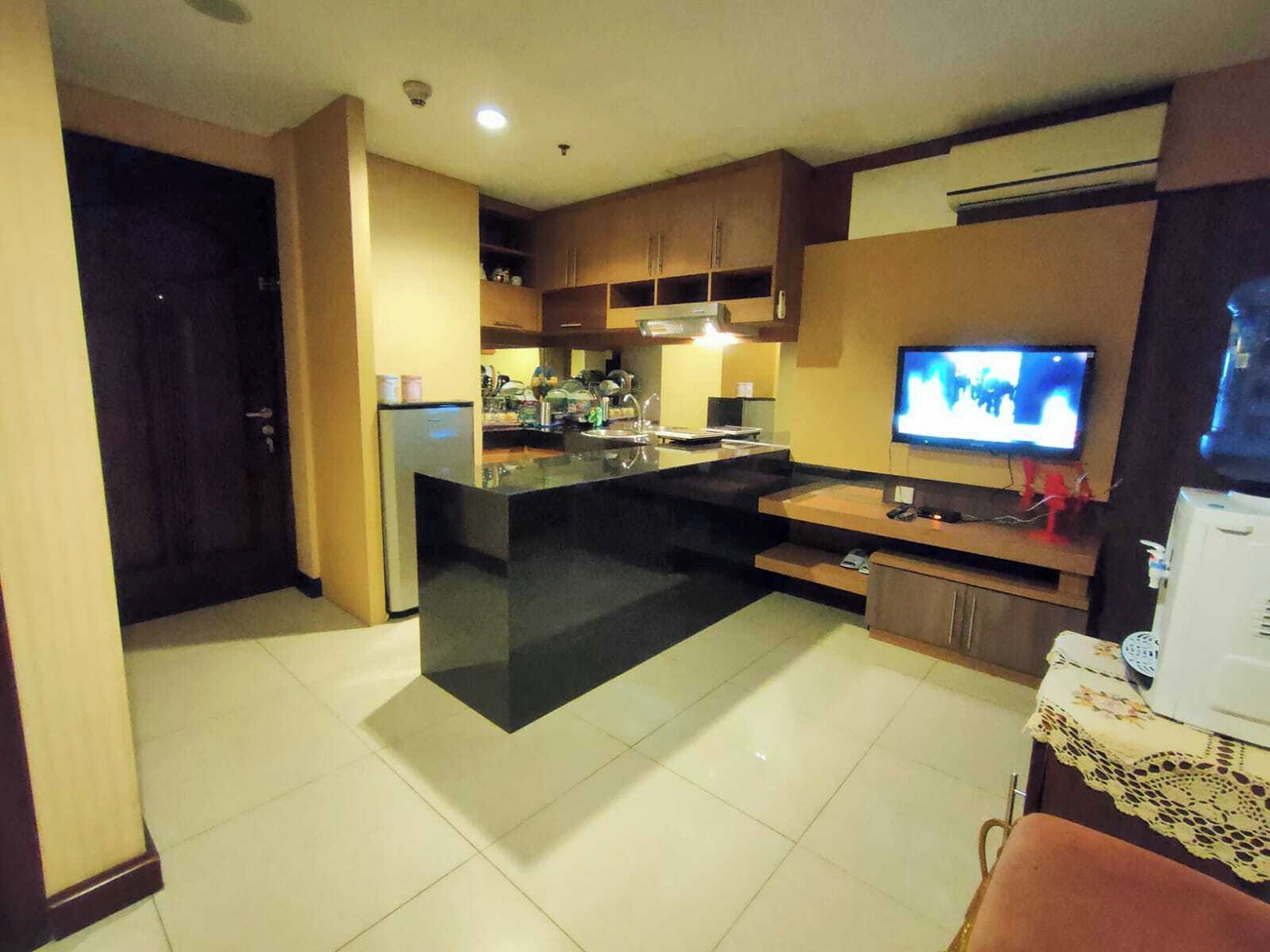 Una cocina compacta con una isla central, horno empotrado y televisor de pantalla plana montado en la pared.
