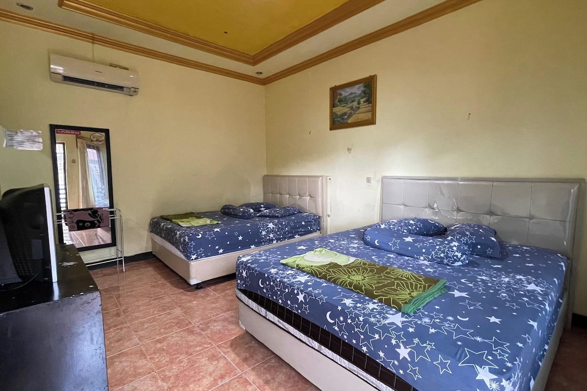 Een kamer met twee bedden, een bureau en een airconditioner.