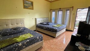 Een hotelkamer met twee bedden, een klein bureau en een raam met gordijnen.