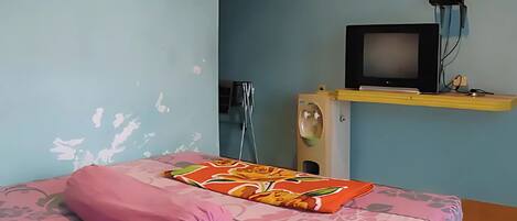 A room with a bed, a television on a stand, and a wall-mounted sink.
