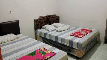 Una habitación con dos camas, una con cubrecama de flores y la otra con cubrecama a rayas.