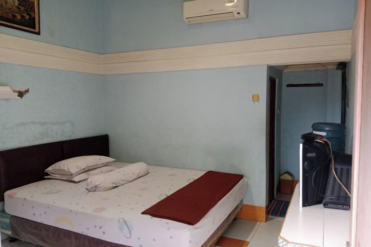 Une chambre à coucher comprenant un lit, des oreillers, une couverture, un appareil de climatisation et un distributeur d’eau.