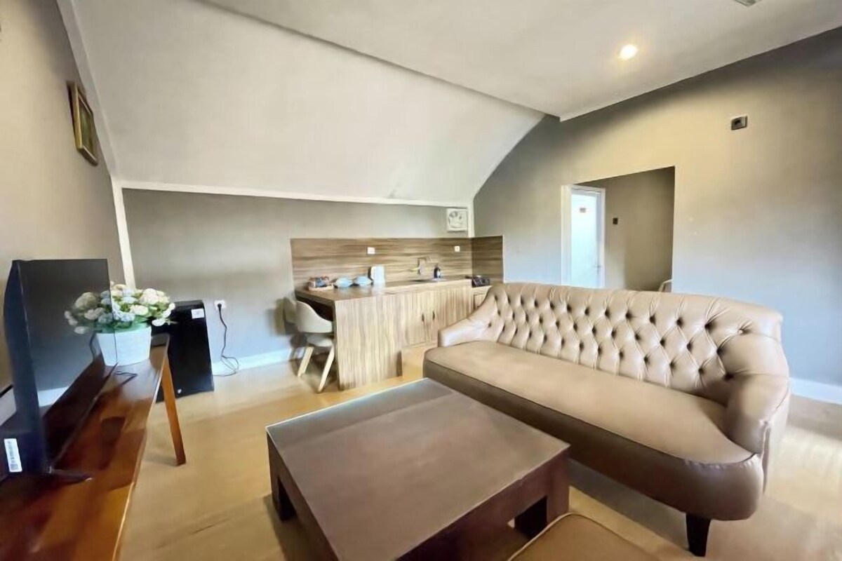 A modern living room with a beige sofa, a wooden coffee table, and a kitchen area in the background.