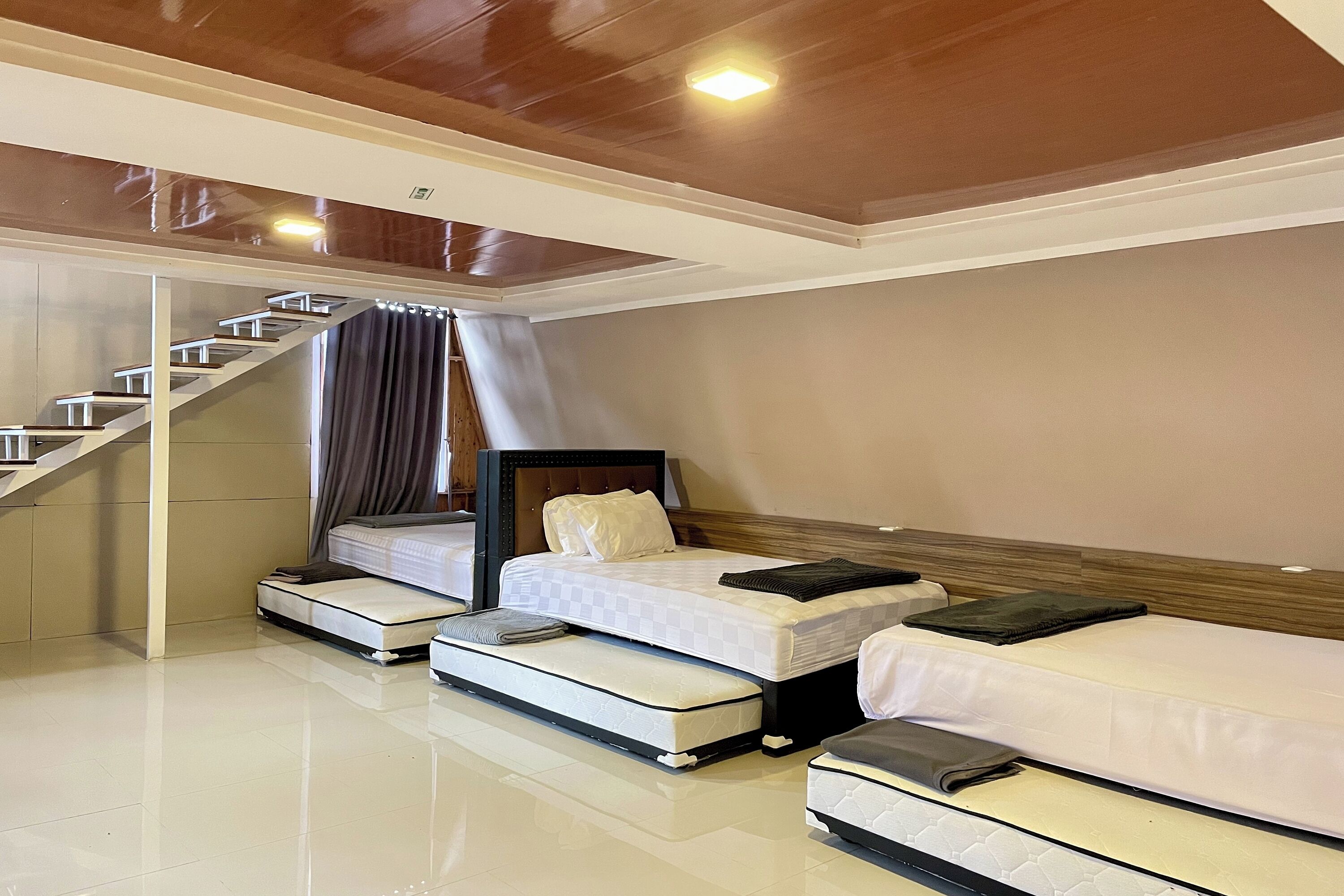 A hotel room with a bed, a smaller bed, a sofa bed, and a staircase.