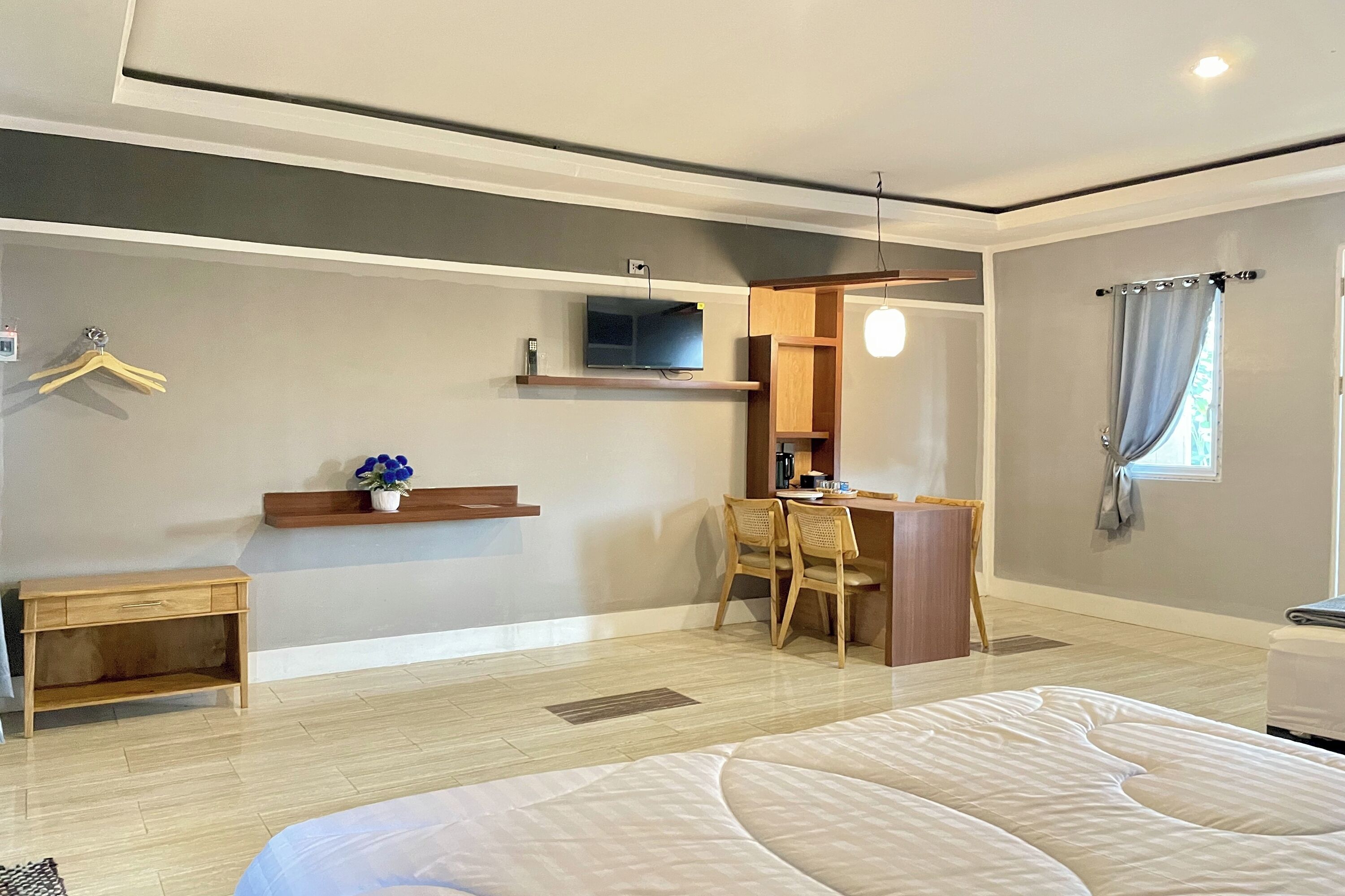 A hotel room with a bed, a desk, a chair, a TV, and a window with curtains.