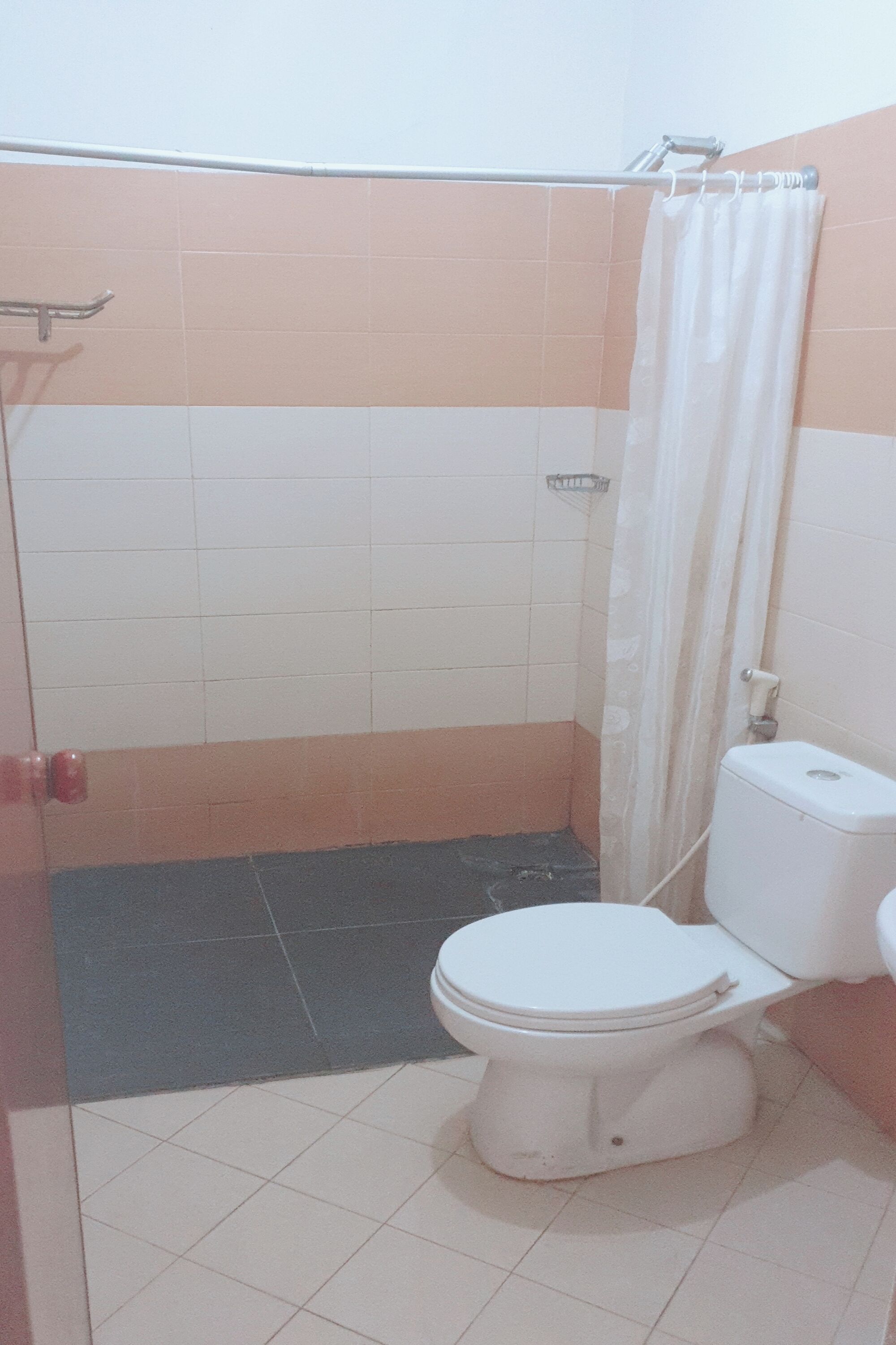 Kylpyhuone, jossa on wc, suihku ja laatoitettu lattia.
