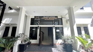 Ingången till Hotel Maison, med en skylt som visar att det är receptionen.