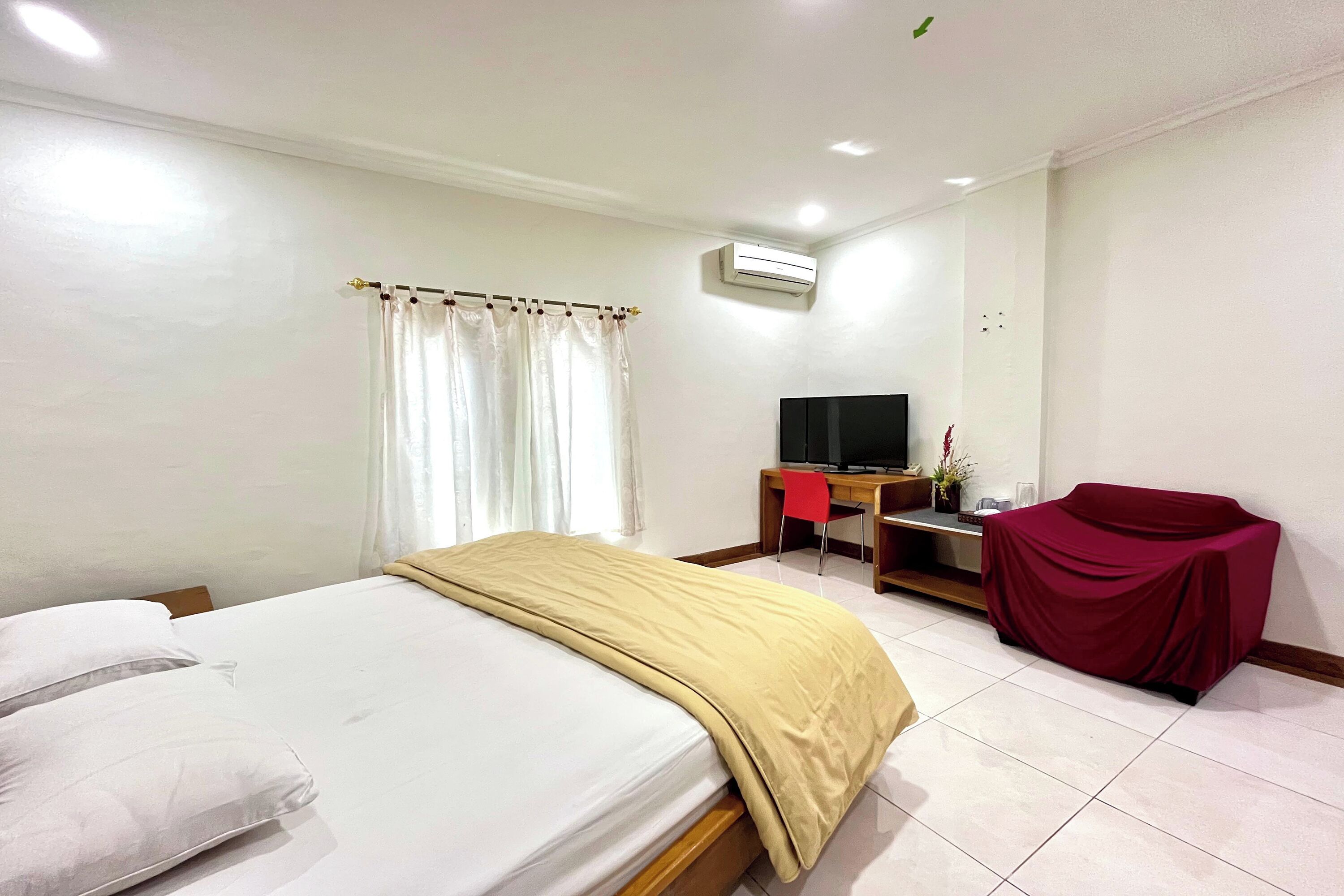 Una habitación de hotel con cama, escritorio con computadora, televisor y sofá tapizado.