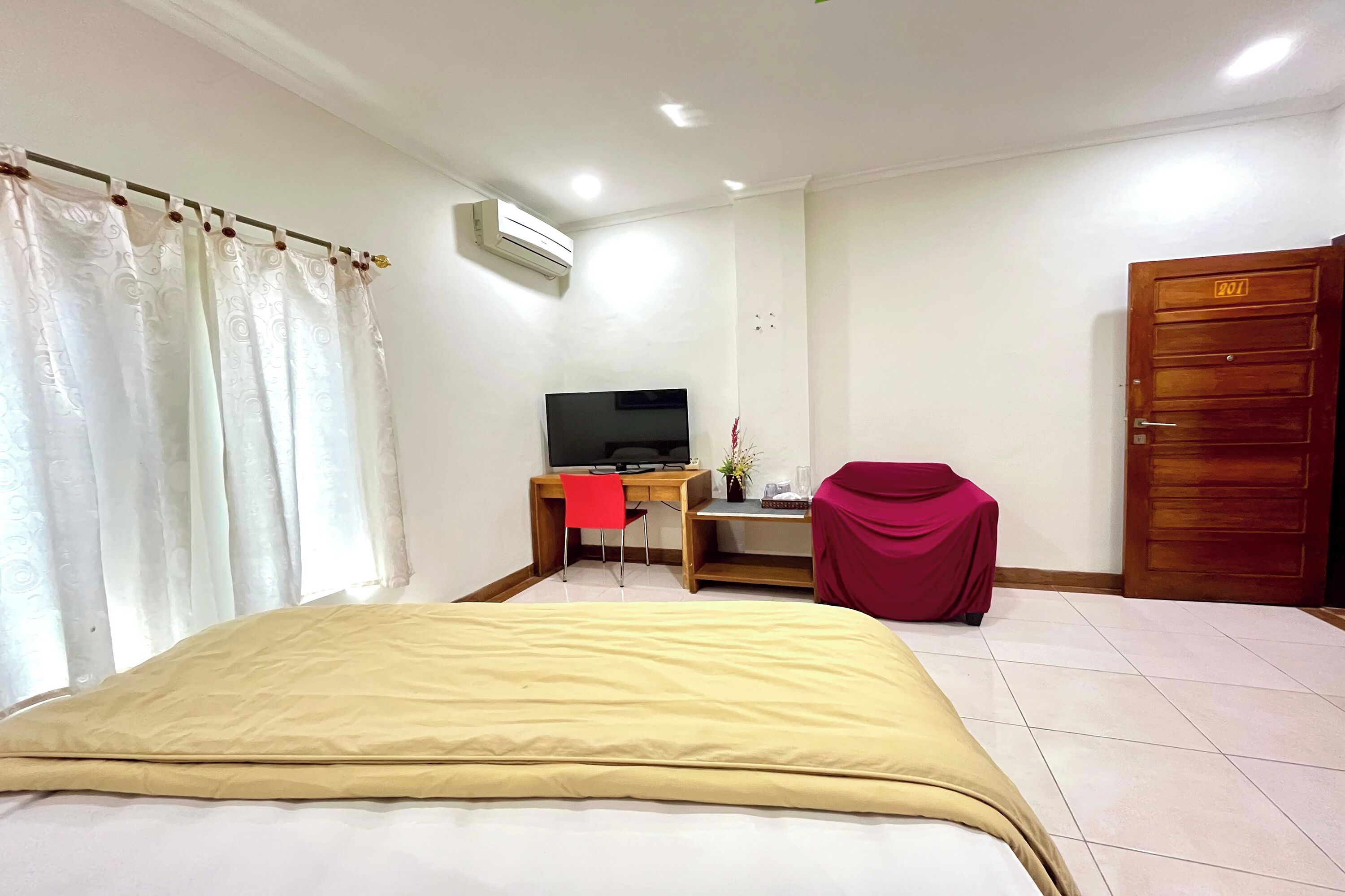 Une chambre d’hôtel avec un lit, un bureau avec une télévision, une chaise et une porte.