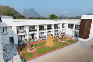 A modern hotel with multiple balconies, a central courtyard with a conical structure, and a mountainous backdrop.