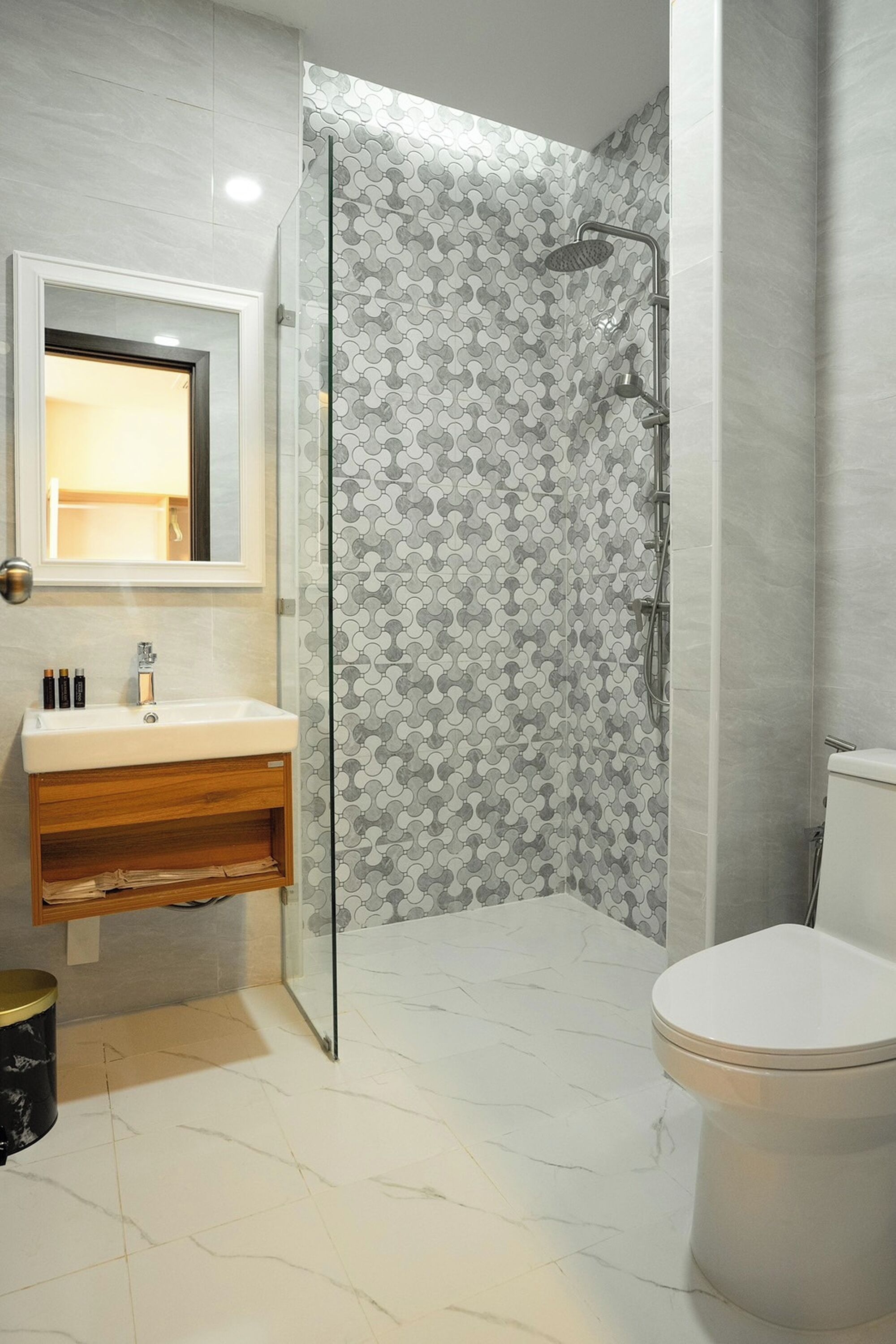A bathroom with a glass-enclosed shower, a white sink with a wooden vanity, and a toilet.