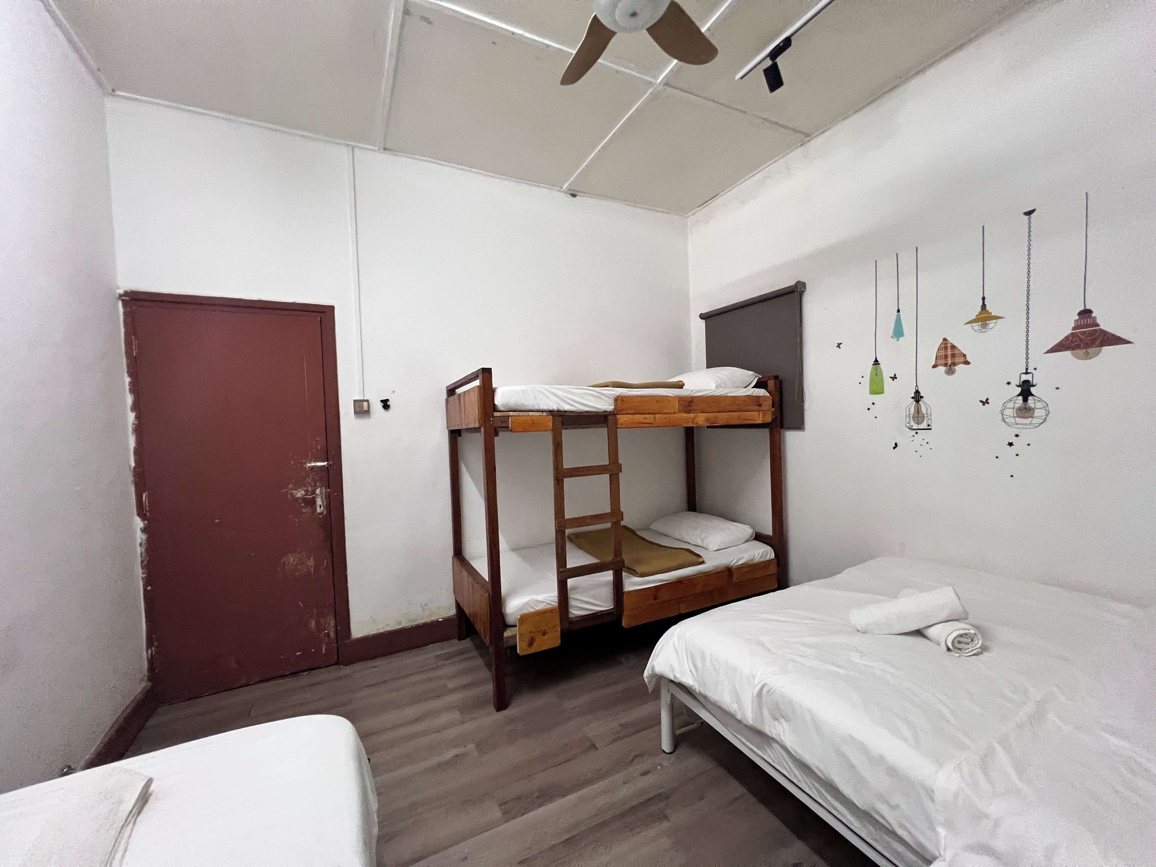 A dormitory room with bunk beds, a ceiling fan, and a door.