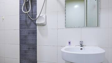 A bathroom with a white sink, a mirror, and a shower unit.