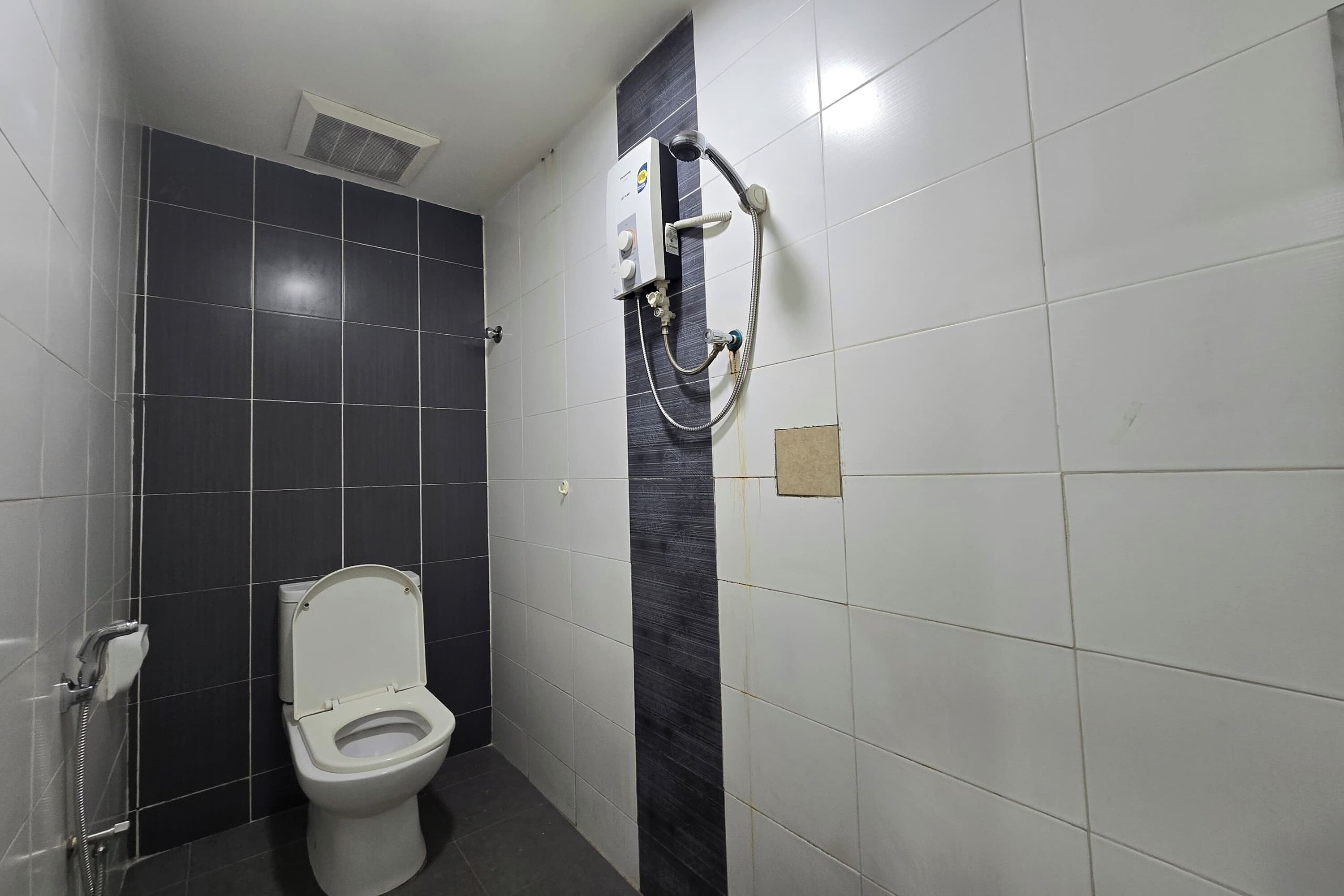 Un baño con inodoro, cabina de ducha y sistema de ventilación.