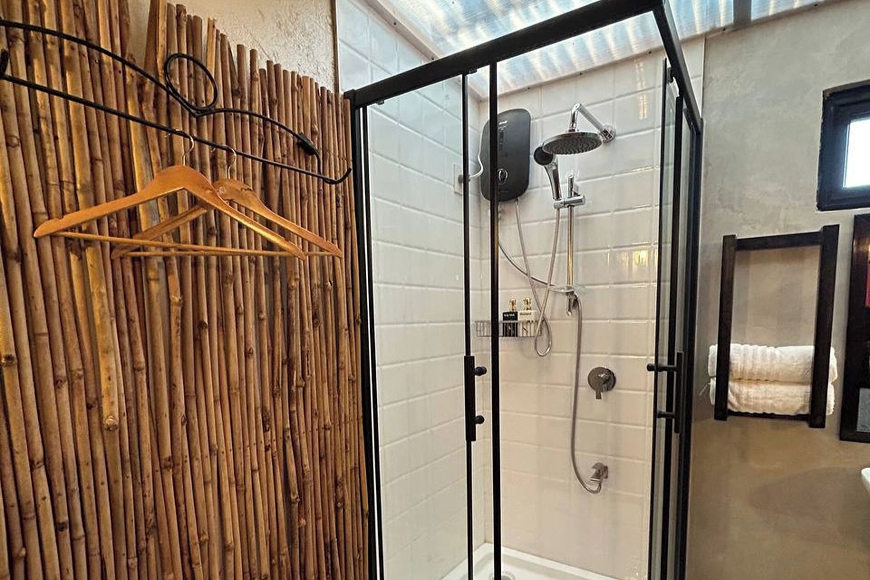 A glass-enclosed shower with a handheld showerhead and a wall-mounted faucet.