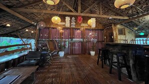 A wooden deck with a bar area, large windows, and hanging wicker lamps. - Balai Balatong (Laoag)