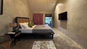 A bedroom with a bed, bedside table, lamp, and a TV on the wall. - Balai Balatong (Laoag)