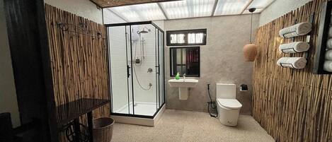 A bathroom with a glass-enclosed shower, a sink, and a toilet.
