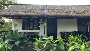A house with a thatched roof and a covered porch. - Balai Balatong (Laoag)