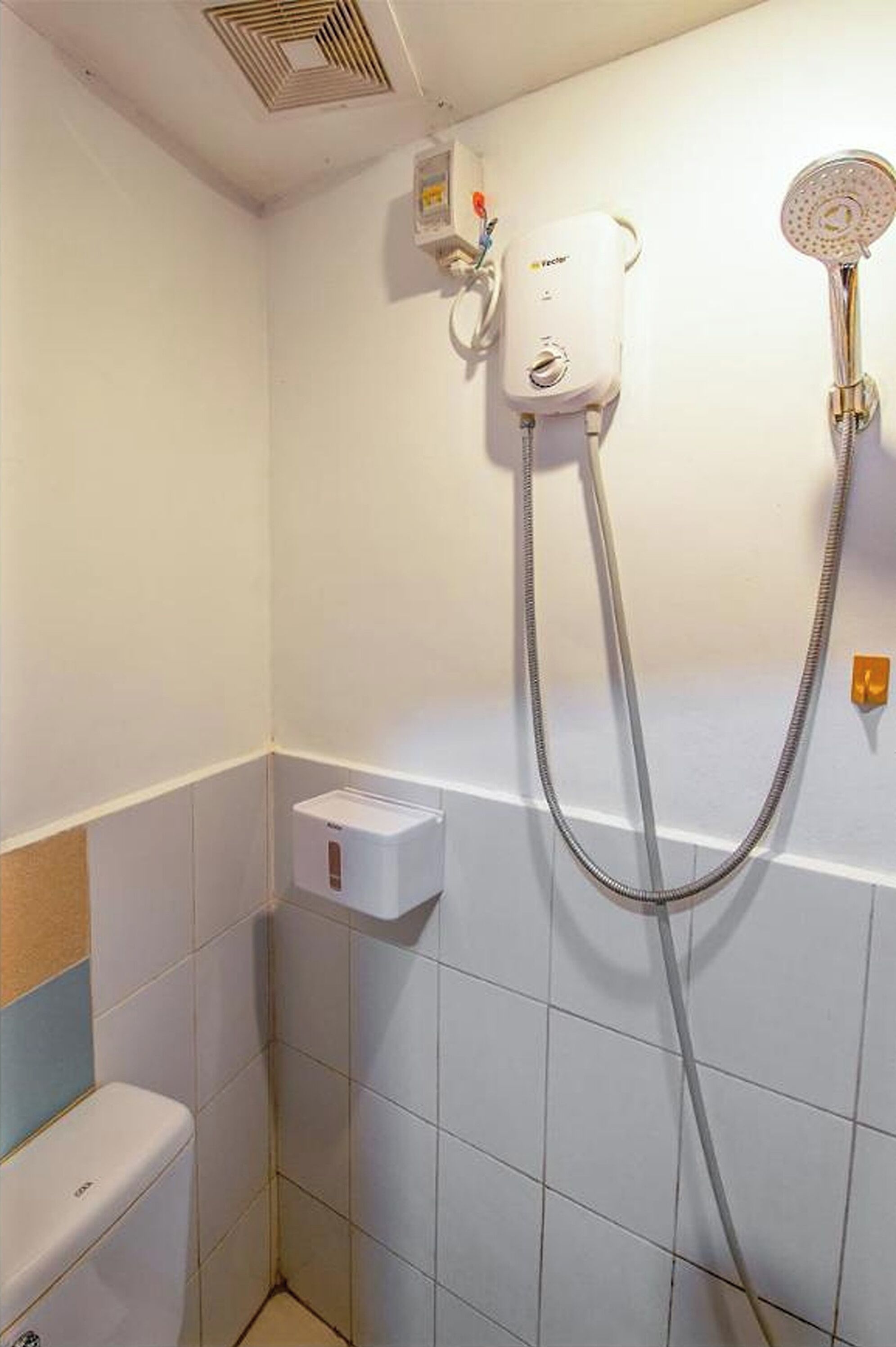 A bathroom with a shower, a toilet, and a towel dispenser.