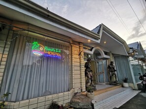 Un hostal con un letrero de neón que anuncia 'Resort's Side HOSTEL LIMPIO Y CÓMODO'.