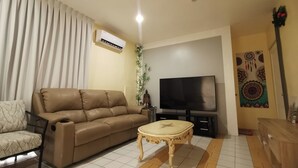 A living room with a sofa, a coffee table, a TV, and a decorative wall piece.