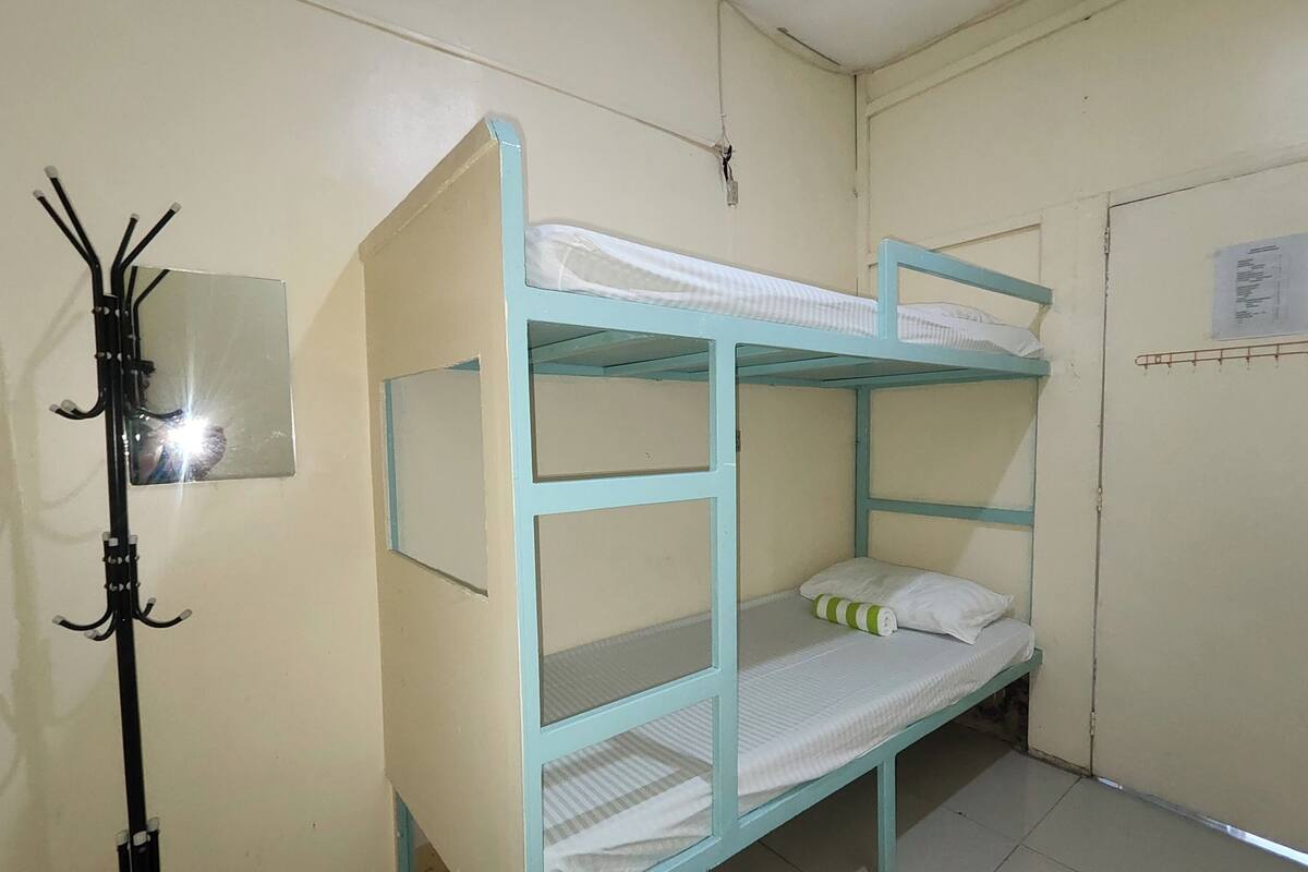 Dormitorio con literas, un perchero y un espejo pequeño.