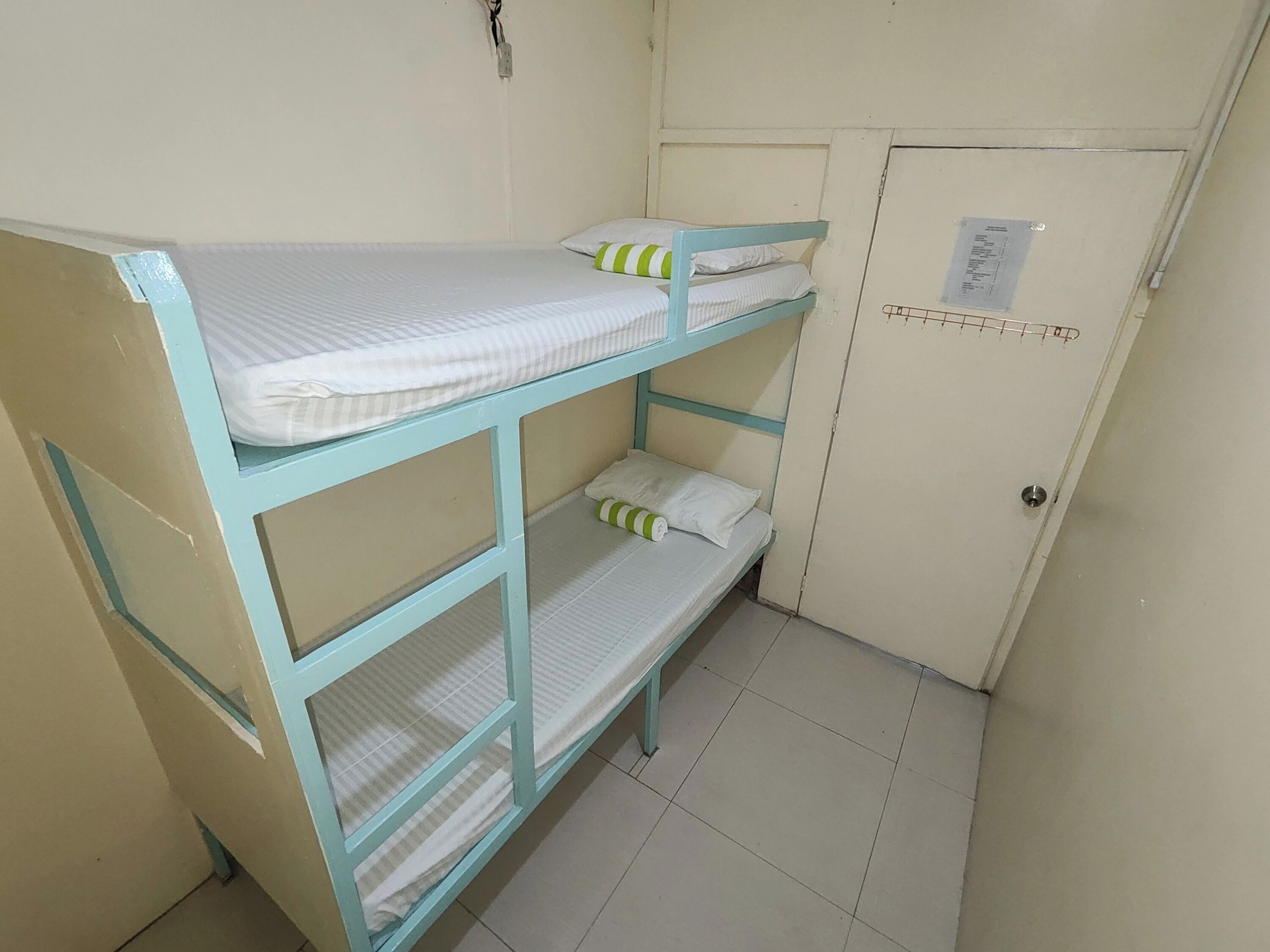 A bunk bed with two levels, a door with a lock, and a small window.