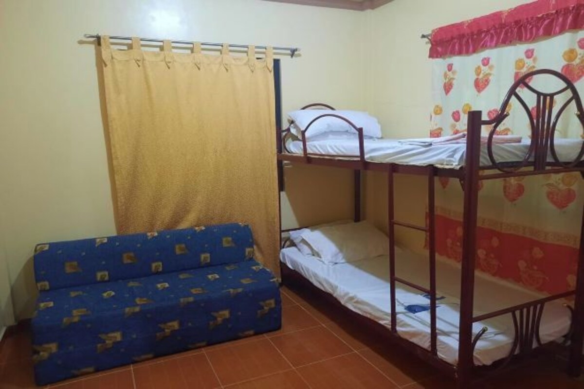 A dormitory room with a bunk bed, a blue sofa, and a curtain.