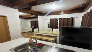 A compact kitchen with a sink, a dining table, and a refrigerator. - Keps Boarding House (San Fernando)