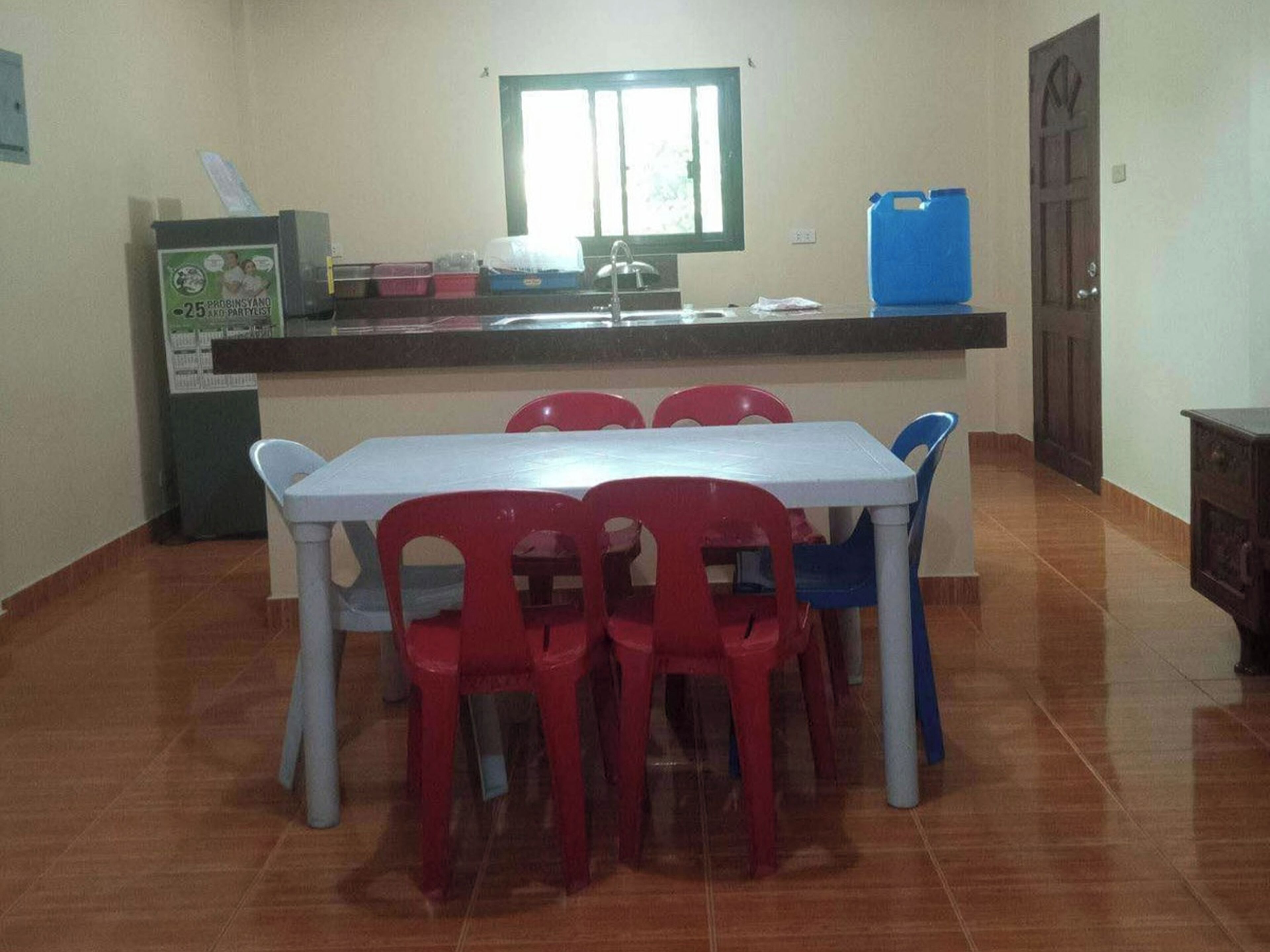 Une petite cuisine équipée d’une table et de chaises, d’une fenêtre et d’un distributeur d’eau.