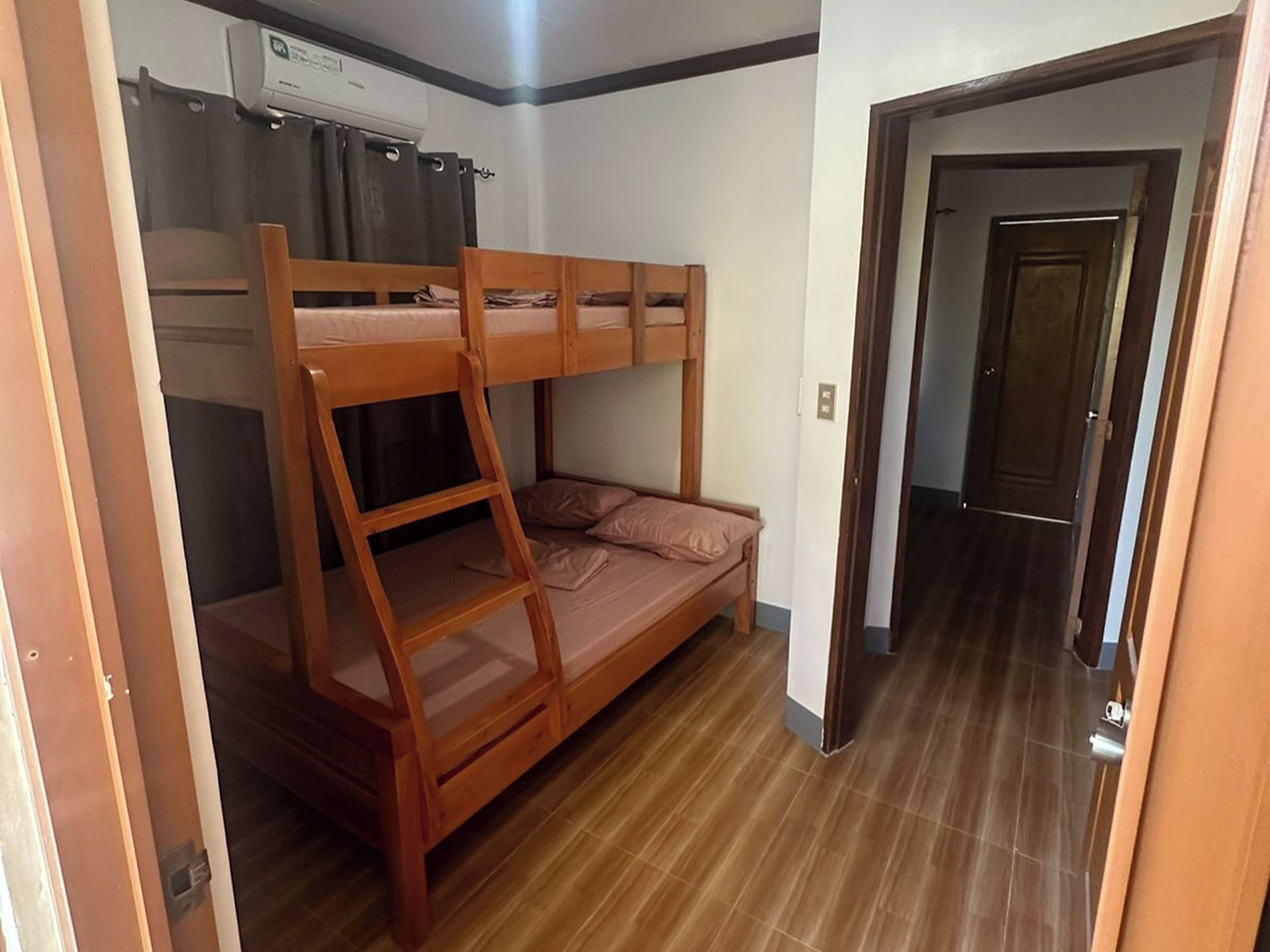 A bunk bed room with a wooden ladder, a small sofa, and a curtain.
