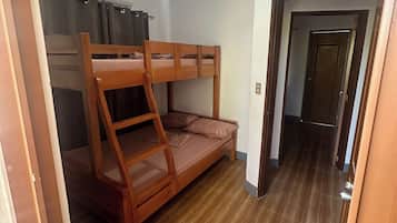 A bunk bed room with a wooden ladder, a small sofa, and a curtain.