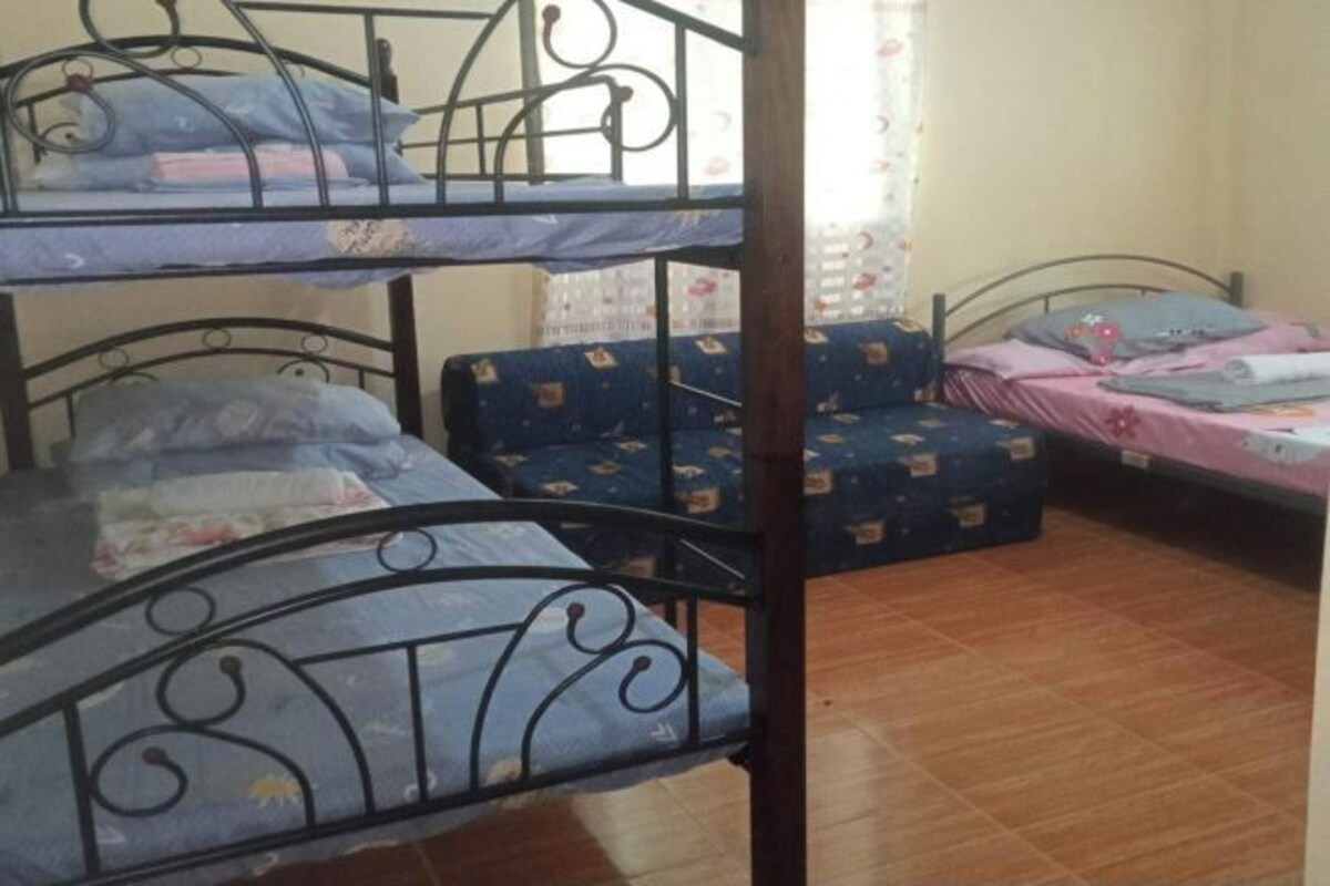 A room with three bunk beds, a small table, and a chair.