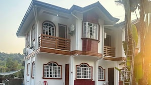A two-story house with a balcony, large windows, and a red door. - Keps Boarding House (San Fernando)