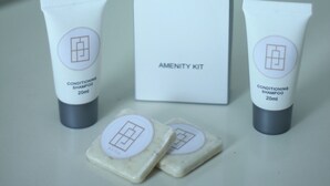 Kit de amenidades do Hotel Paragon, com um frasco de shampoo condicionante, um sabonete em barra e uma caixa.