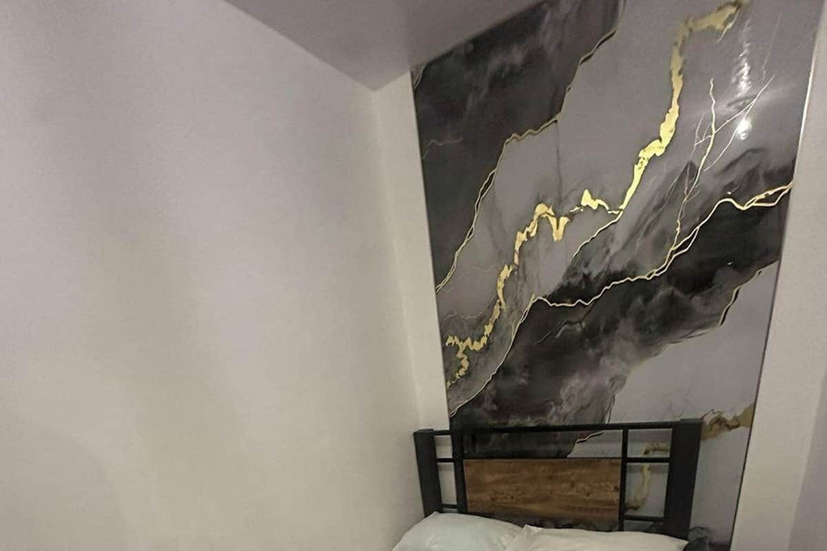 Una cama bien hecha con cabecera de madera, almohada blanca y toalla doblada sobre un colchón blanco liso.