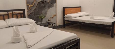 A hotel room with two beds, a marble wall, and a small table with a vase.