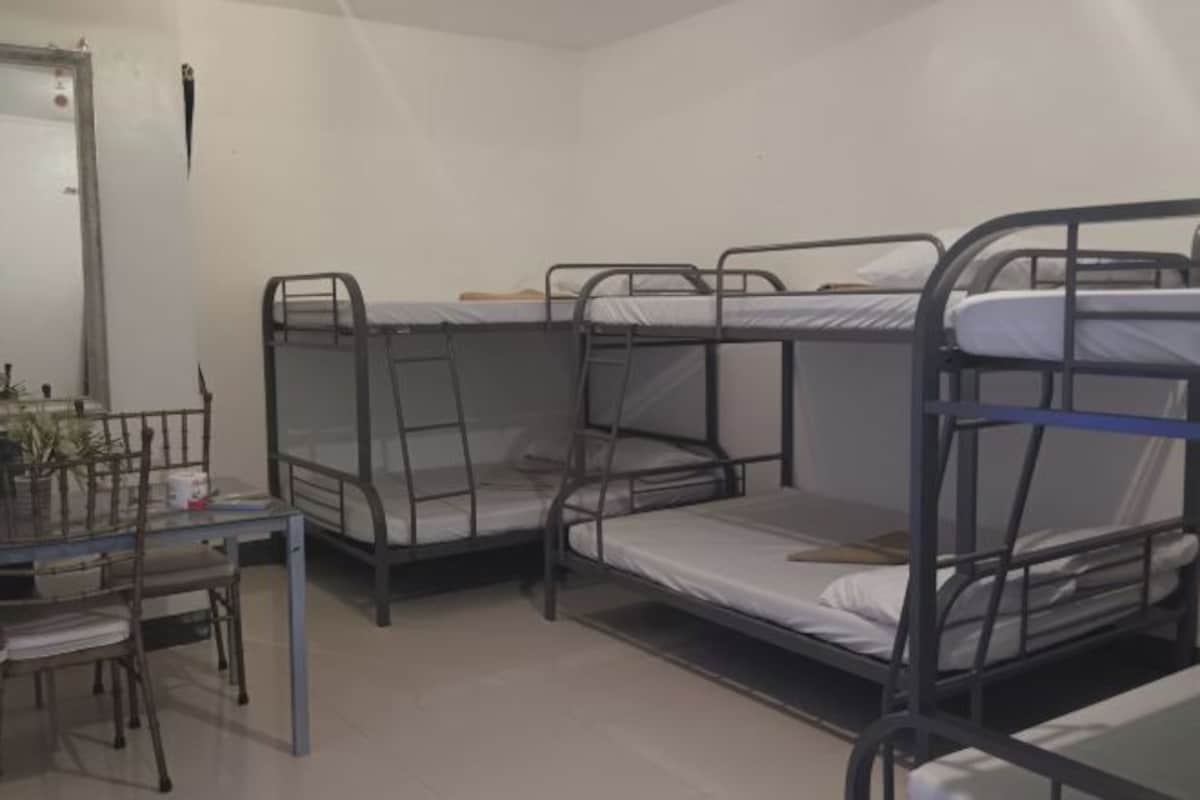 Une chambre de dortoir avec des lits superposés, une petite table avec des chaises et une fenêtre.