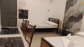 A hotel room with a bed, a wooden chair, a small table, and a marble-patterned table. - Hotel Villarte Fort Pampanga (San Fernando)