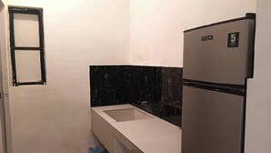 A compact kitchen with a white countertop, a black marble backsplash, and a stainless steel refrigerator. - Hotel Villarte Fort Pampanga (San Fernando)