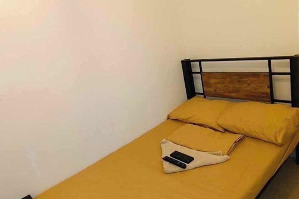 Un lit simple avec une tête de lit en bois et une couvre-lit jaune.