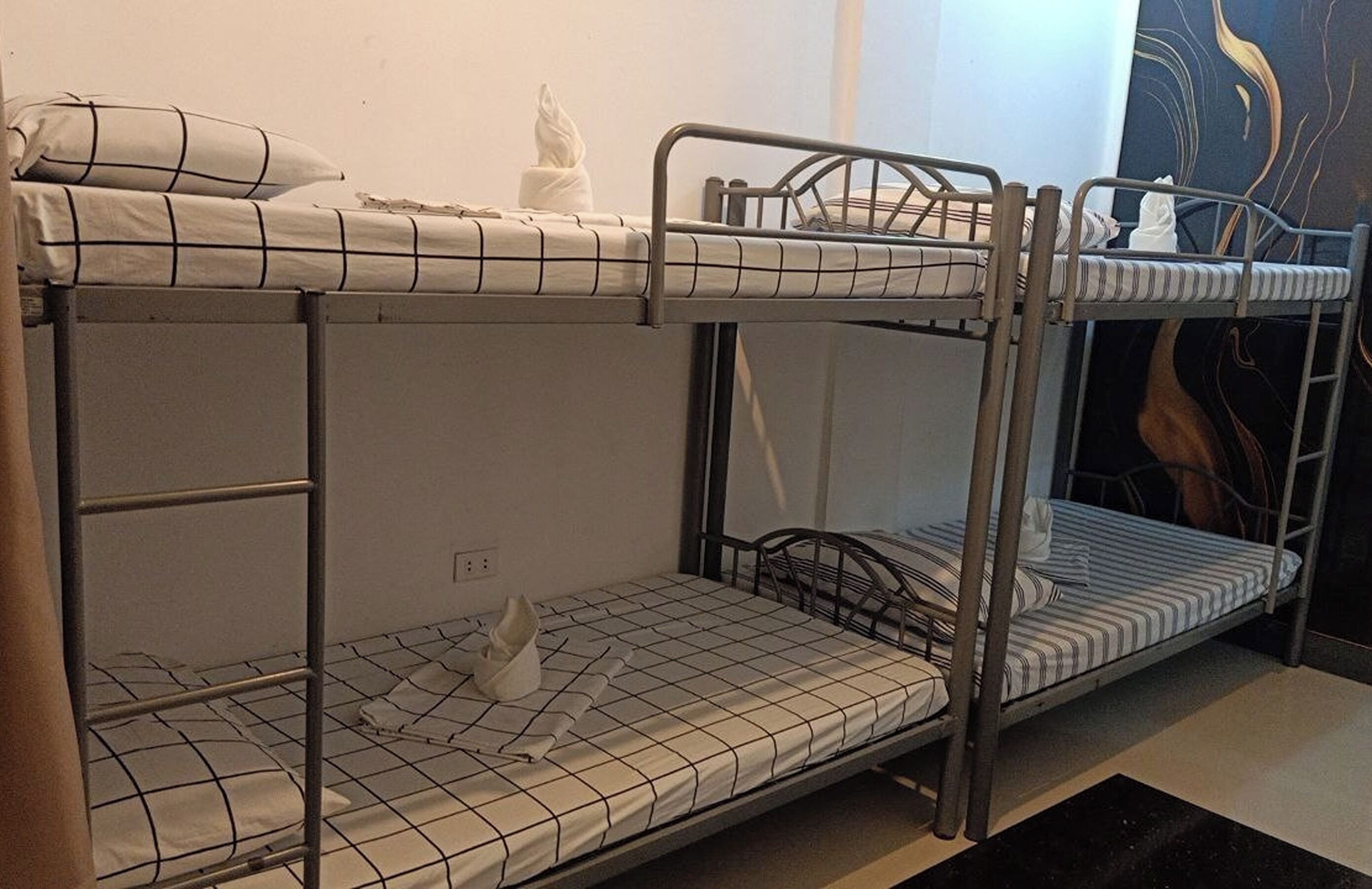 Dormitorio con literas, dos camas, cada una con colchón a rayas y una almohada.